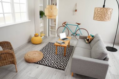 Rahat kanepesi, bisikleti, dizüstü bilgisayarı masa ve lambası olan modern oturma odasının içinde.