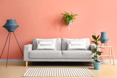 Rahat bir kanepe ve pembe duvarın yanında şık lambalar.