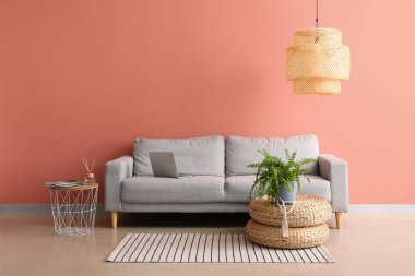 Rahat bir kanepe ve pembe duvarın yanında şık bir lamba.