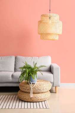 Rahat bir kanepe ve pembe duvarın yanında şık bir lamba.