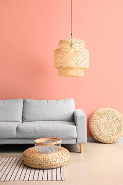 Rahat bir kanepe ve pembe duvarın yanında şık bir lamba.