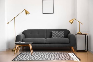 Beyaz duvarın yanında rahat bir kanepe ve modern lambalar.