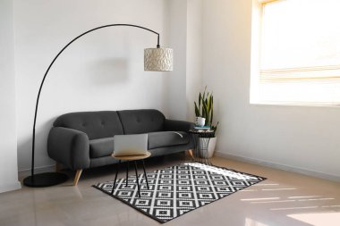 Rahat kanepesi, çiçekleri ve lambası olan modern oturma odası.