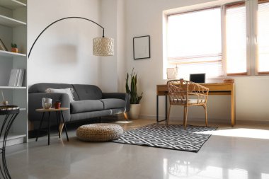 Modern oturma odasının içinde şık bir iş yeri ve rahat bir kanepe var.