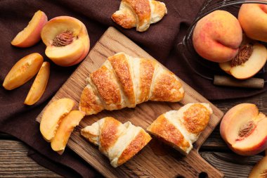 Ahşap arka planda şeftali reçelli lezzetli kruvasanlar.