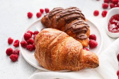 Hafif arka planda ahududu olan lezzetli kruvasan tabağı.