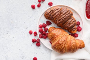 Hafif arka planda ahududu olan lezzetli kruvasan tabağı.