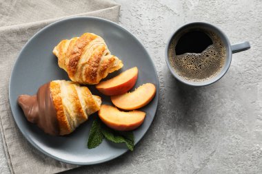 Bir tabak lezzetli kruvasan ve arka planda kahve.