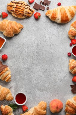 Lezzetli kruvasanlardan yapılmış çerçeve ve arka planda farklı meyveler
