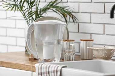 Mutfak tezgahında filtre sürahi ve bir bardak su.