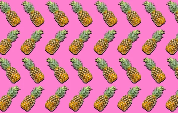 ピンクの背景に熟したパイナップルがたくさんあります デザインのパターン — ストック写真