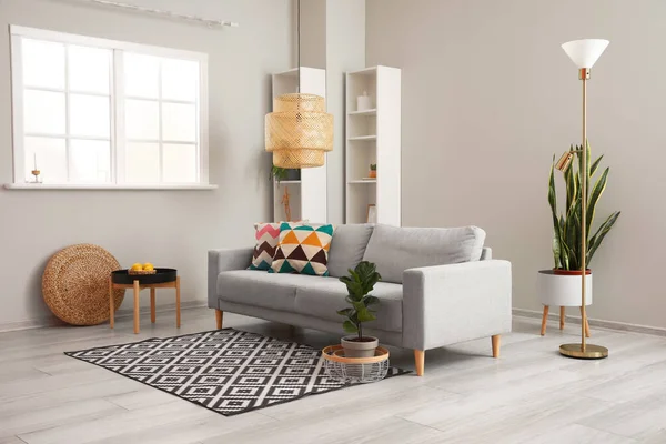 Interior of modern living room with comfortable sofa, lamp and houseplant