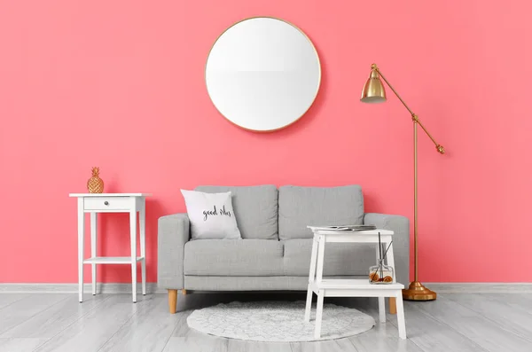 Comfortable sofa and modern lamp near pink wall