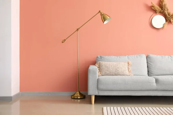 Comfortable sofa and stylish lamp near pink wall