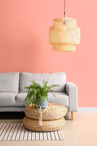 Rahat bir kanepe ve pembe duvarın yanında şık bir lamba.