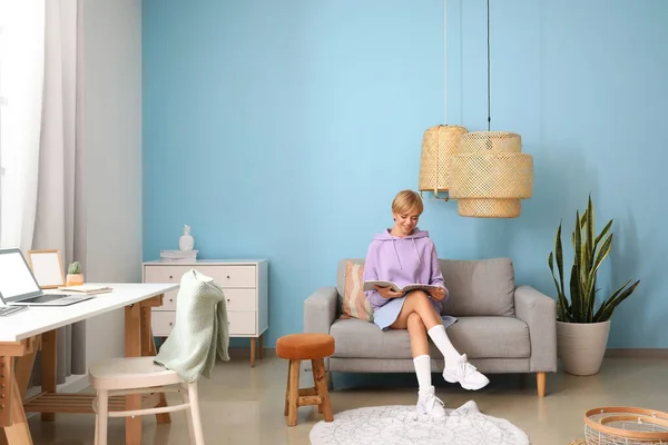 Young Woman Reading Magazine Comfortable Sofa Blue Wall — Stock Photo, Image