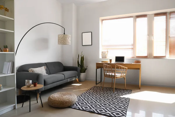 Modern oturma odasının içinde şık bir iş yeri ve rahat bir kanepe var.