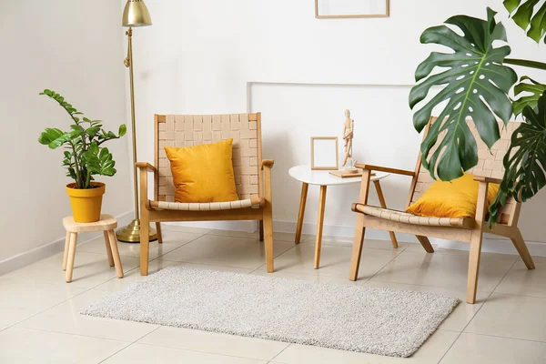 Konforlu koltuklar, masa ve ev bitkisi ışık duvarı yakınında.