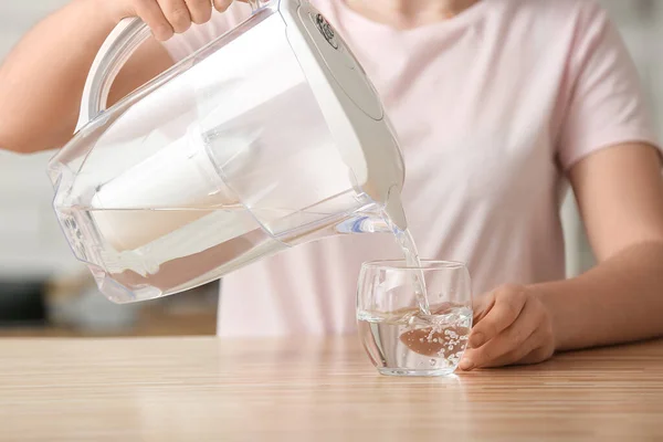 女人们在厨房 特写镜头的桌子上 用滤水罐把纯净水倒入玻璃杯中 — 图库照片