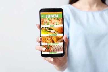 Akıllı telefonlu genç bir kadın internetten yemek sipariş ediyor.