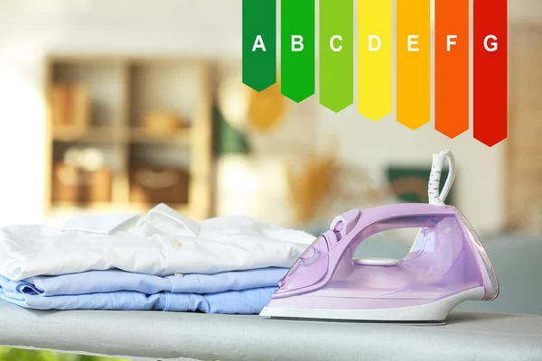 Modern electric iron with clean clothes on board in room. Concept of smart home