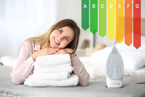 Young woman with clean laundry at home and modern electric iron in room. Concept of smart home