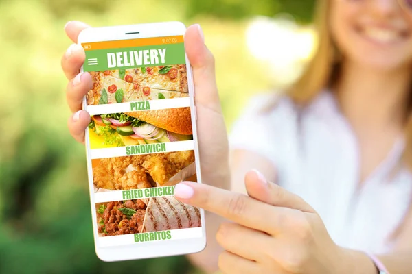 Young woman with smartphone ordering food online, closeup