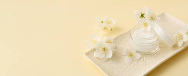 Krema kavanozu ve yasemin çiçekleri metin için alanı olan renk arkaplanı