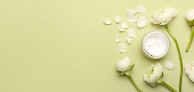 Kozmetik krem kavanozu ve yeşil zemin üzerinde güzel çiçekler metin için yer var.