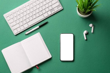 Cep telefonu, not defteri, kulaklıklar, renk arkaplanı üzerinde kalem ve klavye