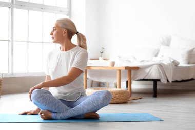 Yetişkin bir kadının evde yoga yaptığı bir sabah.
