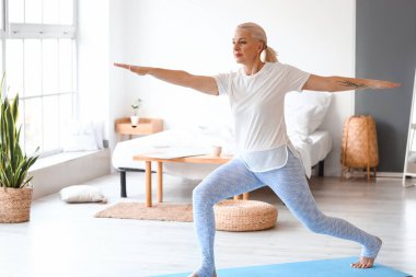Yetişkin bir kadının evde yoga yaptığı bir sabah.