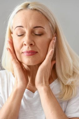 Olgun bir kadının evde yüz kremi sürdüğü bir sabah.