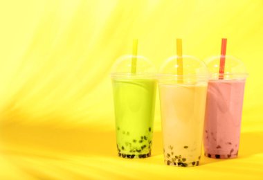 Sarı arka planda farklı lezzetli köpüklü plastik fincanlar.