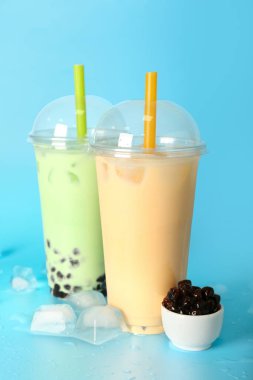 Mavi zemin üzerinde böğürtlen ve buz küpleri olan plastik fincanlar.