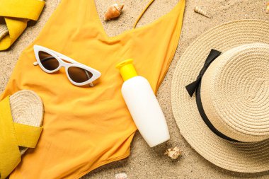 Plaj aksesuarlarıyla güneş kremi ve kumdaki deniz kabukları.