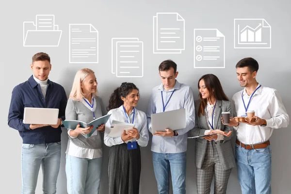 Colleagues with laptops, cups of coffee and digital files on light background