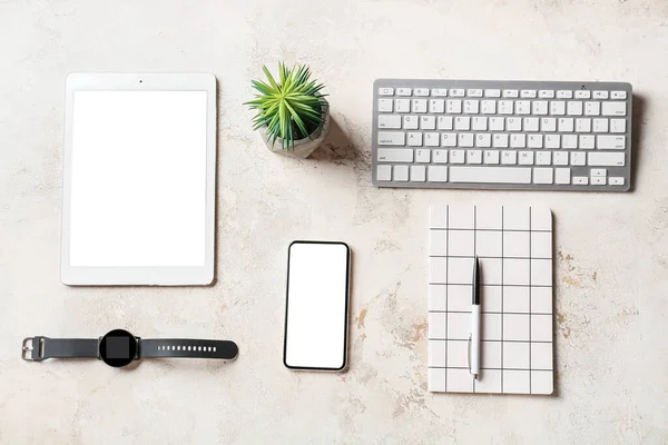 Mobile phone, tablet computer, wrist watch, keyboard and notebook on light background