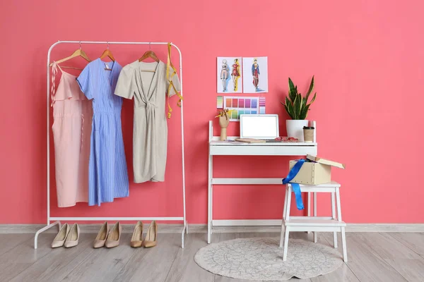 Workplace of clothes stylist and rack with apparel near pink wall