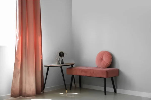 Pink bench with cushion and table in light room