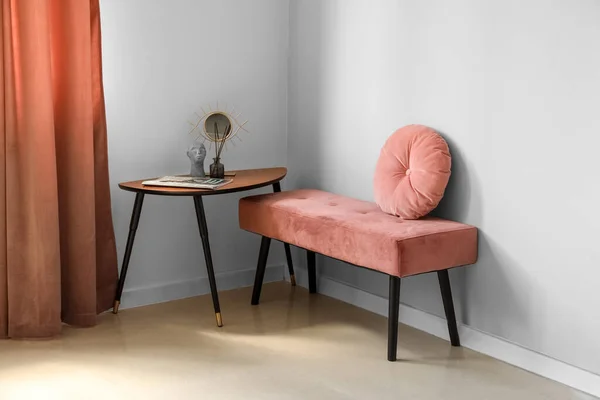 Pink bench with cushion and table in light room