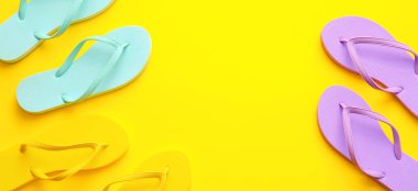 Sarı arkaplanda, yazı için yeri olan şık parmak arası terlikler seti, üst görünüm