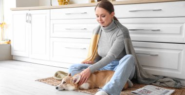 Mutfakta Corgi köpeği olan genç ve güzel bir kadın.