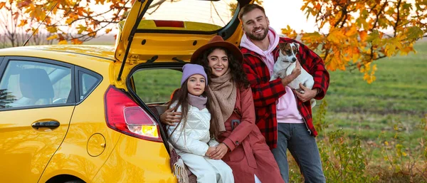 Happy family with dog near car outdoors on autumn day