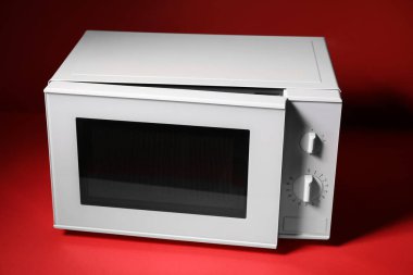 Kırmızı zemin üzerinde yeni modern mikrodalga fırın