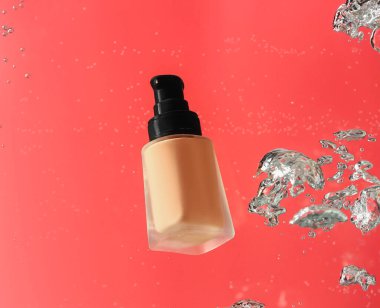 Renk arkaplanındaki suda bir şişe makyaj temeli