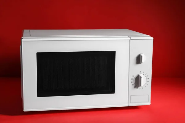 New modern microwave oven on red background