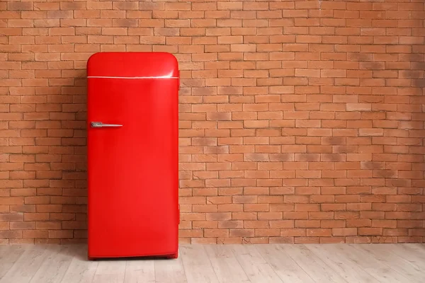Stylish retro fridge near brick wall in room