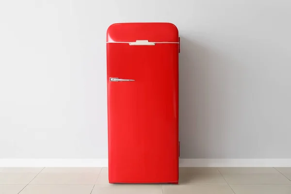 Stylish retro fridge near light wall in room