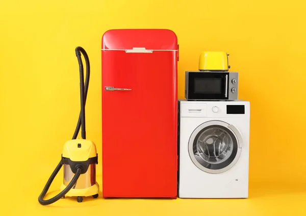 Modern household appliances on yellow background